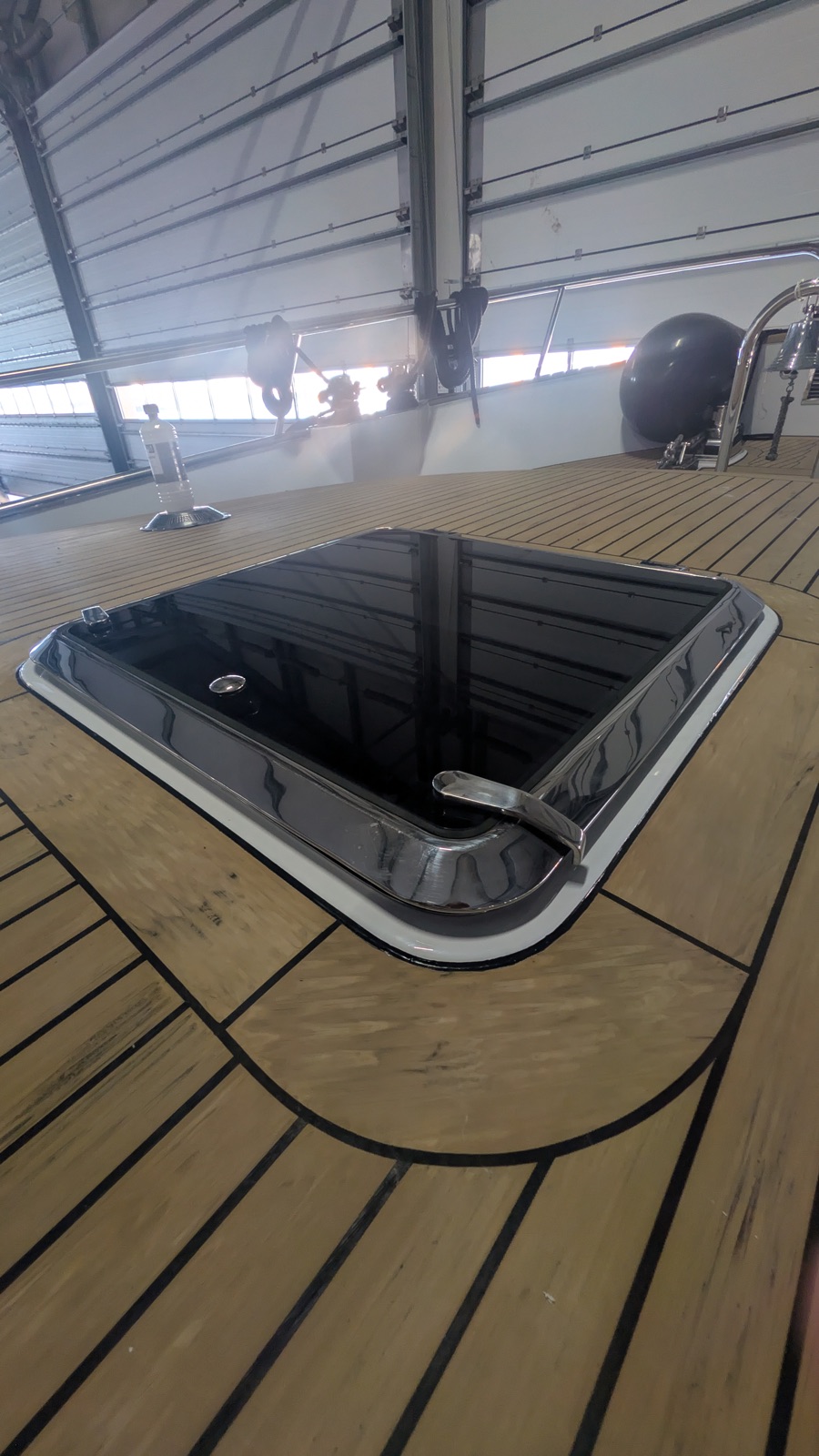 Zwart gelakt dekluik op het teakdek van een boot