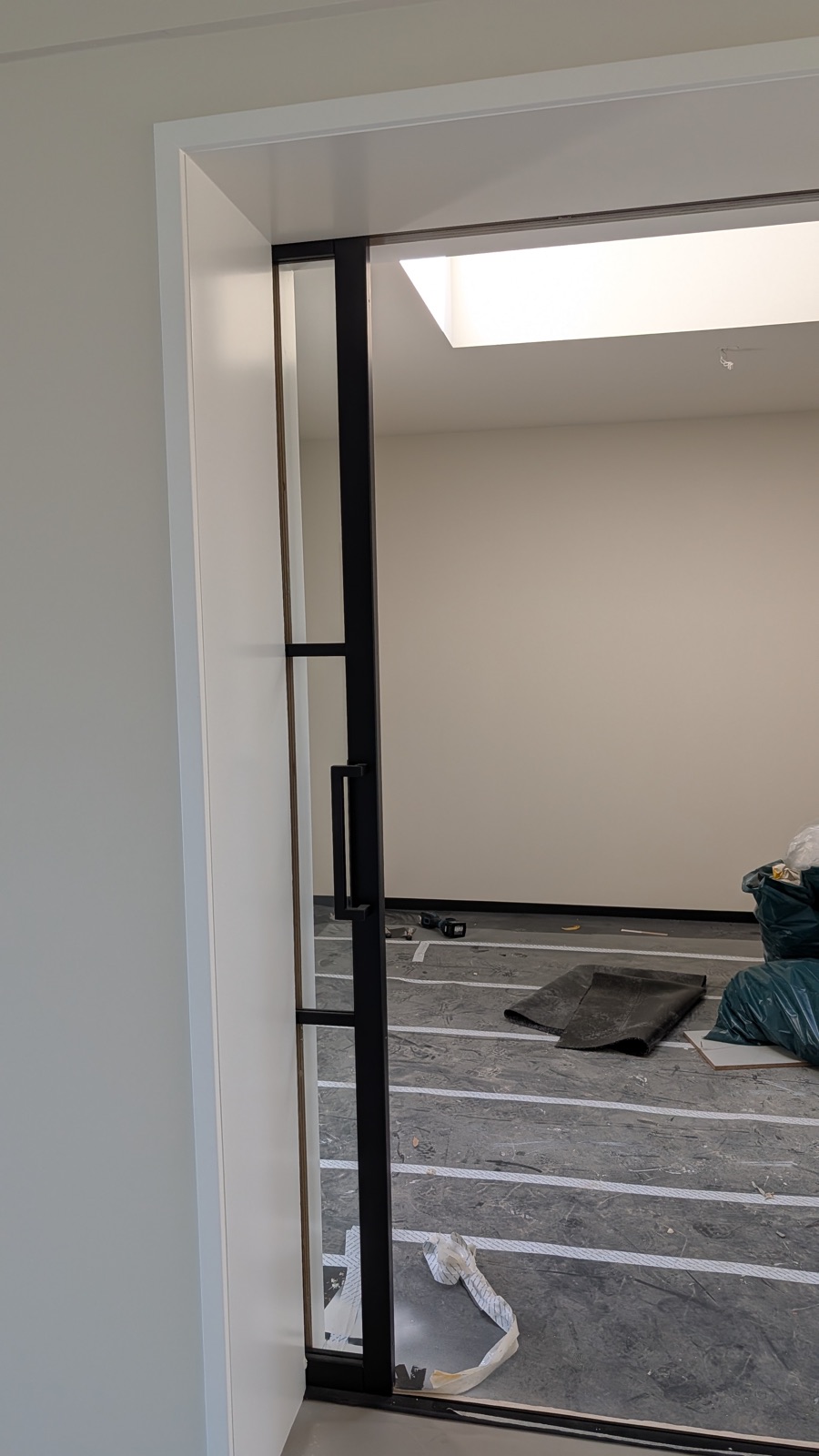 Stalen taatsdeur met zwart kozijn in een strak wit afgewerkte woning