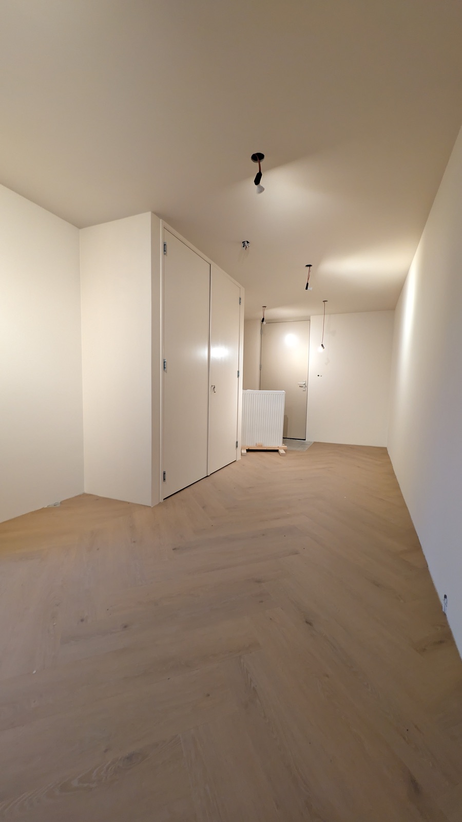 Strak wit gespoten wanden en plafond in een nieuwe woonruimte met kastenwand